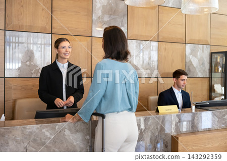 Female receptionist assisting woman guest at hotel front desk Female receptionist assisting woman guest at hotel front desk 143292359