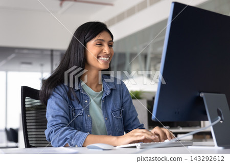 Happy Indian office employee working on computer in modern office 143292612