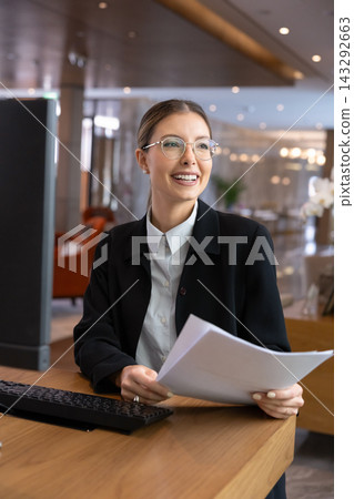 Smiling female hotel staff receptionist working at front desk Smiling female hotel staff receptionist working at front desk 143292663