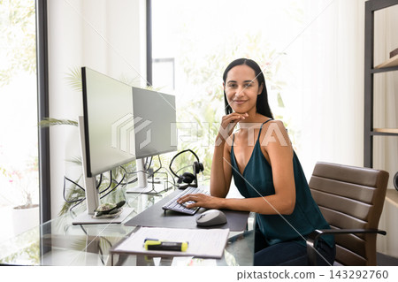 Confident woman working at dual monitor home office Confident woman working at dual monitor home office 143292760