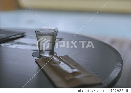 桌上放著一杯水,背景是游泳池。 桌上放著一杯水,背景是游泳池。 143292846