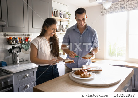 Couple preparing together morning sandwiches for breakfast Couple preparing together morning sandwiches for breakfast 143292958