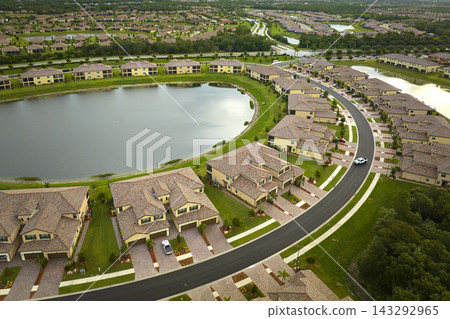 Aerial view of tightly located family houses with retention ponds to prevent flooding in Florida closed suburban area. Real estate development in american suburbs Aerial view of tightly located family houses with retention ponds to prevent flooding in Florida closed suburban area. Real estate development in american suburbs 143292965