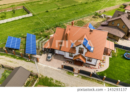 Aerial top view of new modern residential house cottage with blue shiny solar photo voltaic panels system on roof. Renewable ecological green energy production concept. Aerial top view of new modern residential house cottage with blue shiny solar photo voltaic panels system on roof. Renewable ecological green energy production concept. 143293137