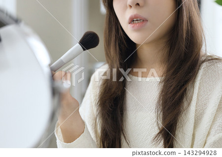 一位二十多歲的女性正在化妝的側面照。 143294928