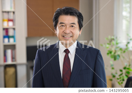 一位六十多歲的男子在辦公室窗邊微笑。 一位六十多歲的男子在辦公室窗邊微笑。 143295005