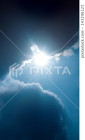 Bright sun shining through dark, dramatic clouds in a clear blue sky, creating a stunning contrast of light and shadow, with sun rays radiating outward. Nature, natural, or quotes background Bright sun shining through dark, dramatic clouds in a clear blue sky, creating a stunning contrast of light and shadow, with sun rays radiating outward. Nature, natural, or quotes background 143296125