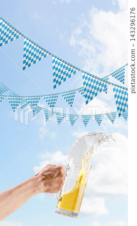 A person holds a large glass beer mug, spilling and splashing beer against a background of bright blue sky with white clouds and traditional Bavarian checkered pennants. Bavarian Oktoberfest Festival A person holds a large glass beer mug, spilling and splashing beer against a background of bright blue sky with white clouds and traditional Bavarian checkered pennants. Bavarian Oktoberfest Festival 143296176