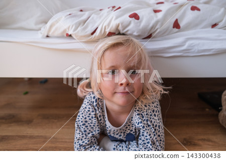 blonde little girl in pajamas lying on wooden floor in cozy bedroom blonde little girl in pajamas lying on wooden floor in cozy bedroom 143300438