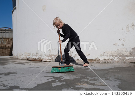 girl in black wetsuit sweeping wet concrete terrace with broom on sunny day girl in black wetsuit sweeping wet concrete terrace with broom on sunny day 143300439