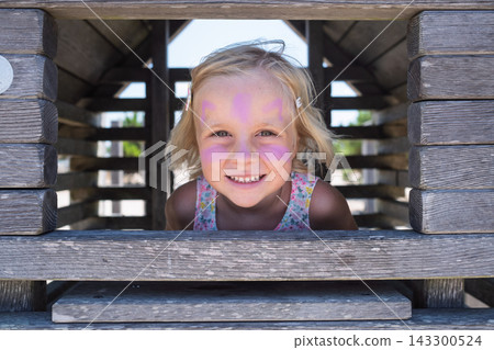 Girl Looking Out from a Wooden Playground Structure 143300524