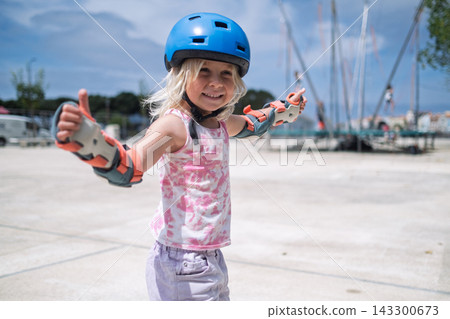 Cute Blonde Toddler in Safety Equipment Giving Thumbs Up Gesture Outdoors Cute Blonde Toddler in Safety Equipment Giving Thumbs Up Gesture Outdoors 143300673