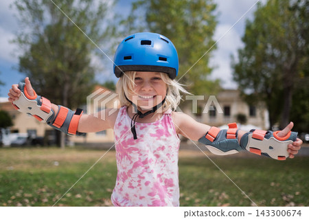 Cute Blonde Toddler in Safety Equipment Giving Thumbs Up Gesture Outdoors 143300674