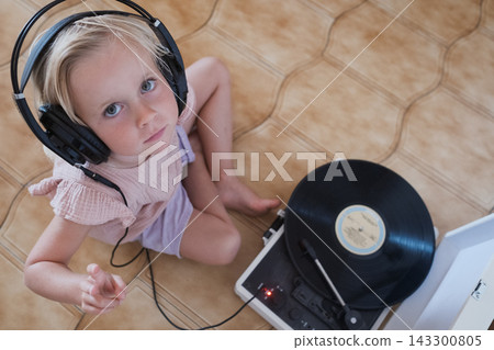 girl wearing large black headphones putting a needle on a vinyl record girl wearing large black headphones putting a needle on a vinyl record 143300805