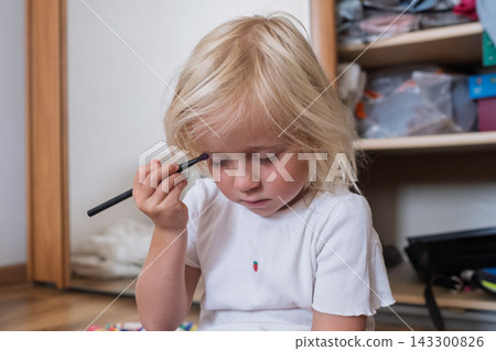 Little Girl Applying Makeup with a Brush at Home 143300826