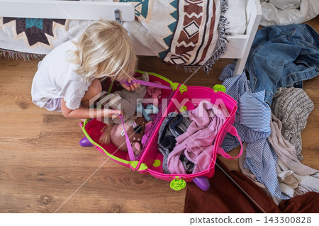londe Toddler Girl Packing Toys and Clothes into a Bright Luggage in Her Bedroom londe Toddler Girl Packing Toys and Clothes into a Bright Luggage in Her Bedroom 143300828