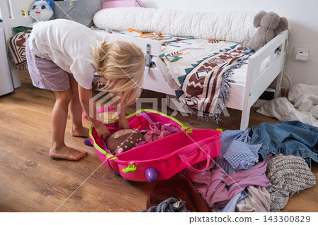 londe Toddler Girl Packing Toys and Clothes into a Bright Luggage in Her Bedroom londe Toddler Girl Packing Toys and Clothes into a Bright Luggage in Her Bedroom 143300829