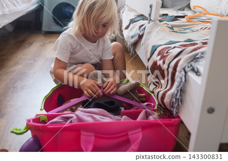 londe Toddler Girl Packing Toys and Clothes into a Bright Luggage in Her Bedroom londe Toddler Girl Packing Toys and Clothes into a Bright Luggage in Her Bedroom 143300831