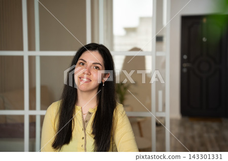 Smiling woman in yellow sleepwear sitting at home in a relaxed lifestyle portrait. Women's sleepwear everyday comfort self-confidence and home living Smiling woman in yellow sleepwear sitting at home in a relaxed lifestyle portrait. Women's sleepwear everyday comfort self-confidence and home living 143301331