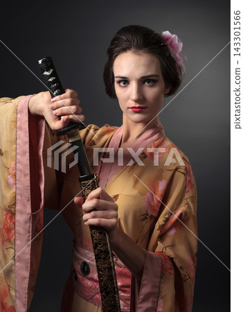Elegant woman in a floral Japanese kimono holding a traditional katana. 143301566