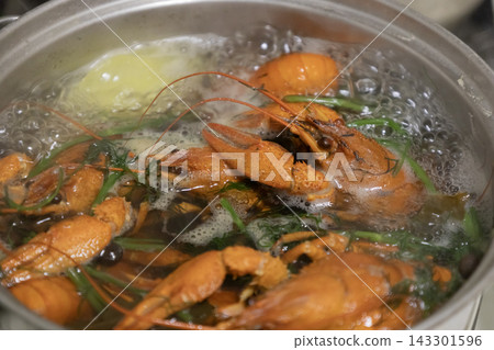 Fresh crayfish (crawfish) boiling vigorously in a large metal cooking pot filled with water, herbs, dill, and spices on a kitchen stovetop. The shellfish are bright orange-red and submerged. Fresh crayfish (crawfish) boiling vigorously in a large metal cooking pot filled with water, herbs, dill, and spices on a kitchen stovetop. The shellfish are bright orange-red and submerged. 143301596