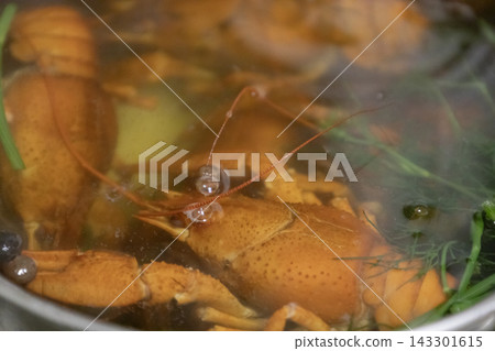 Vibrant orange crayfish boiling in a pot with aromatic herbs, dill, and peppercorns. Close-up shot of traditional seafood preparation, rich steam visible. 143301615