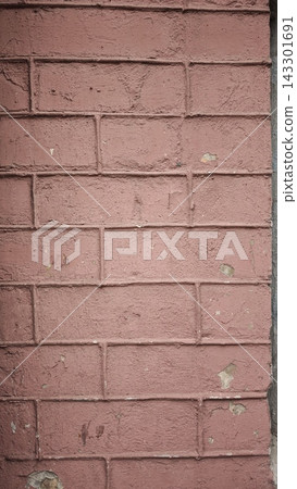 Textured pink brick wall with visible mortar joints and minor surface imperfections, showcasing a rustic and weathered appearance in an urban setting 143301691