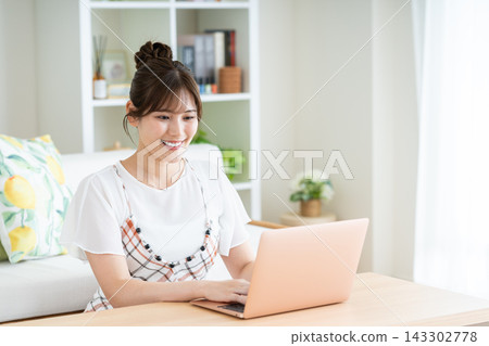 使用一台電腦在客廳裡的年輕女子 143302778