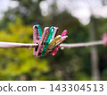 Many colorful plastic clothespin hanging on the wire with raindrop 143304513