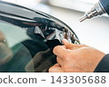 A car wrapping specialist applies a polyurethane film to the car. Detailer PPF 143305688