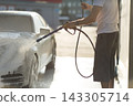 Worker washing car at self-service car wash 143305714