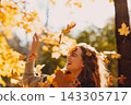 Smiling young woman throws up the autumn leaves in the forest at sunset. 143305717