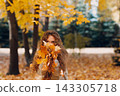 Smiling young woman collects leaves for the herbarium in the forest at sunset. 143305718
