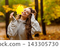 Young laughing woman holds yellow leaf in her hand in the park at sunset. 143305730