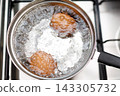 Saucepan stainless steel with boiling eggs breakfast in a water on a gas stove 143305732