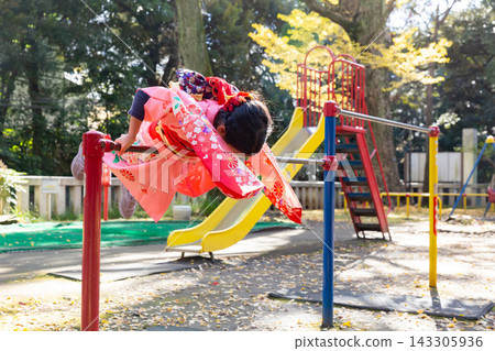 一個女孩穿著和服在單槓上旋轉,另一個孩子在公園的遊樂設施上玩耍,兩人都穿著正式的振袖和服。 一個女孩穿著和服在單槓上旋轉,另一個孩子在公園的遊樂設施上玩耍,兩人都穿著正式的振袖和服。 143305936