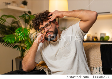 Arabian man sad at night after bad news indoors sitting on couch feels stressed very tired and upset 143306427