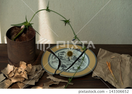 A still life with a broken plate and dried flowers symbolizes the fragility of life and the breakdown of relationships. A still life with a broken plate and dried flowers symbolizes the fragility of life and the breakdown of relationships. 143306652