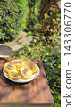 A plate piled high with fresh, juicy sliced gold kiwis against a green background. 143306770
