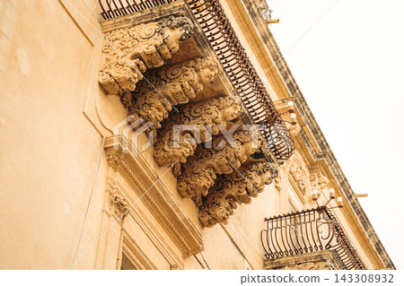 Baroque architectural details in Noto Sicily featuring grotesque figures supporting a balcony Baroque architectural details in Noto Sicily featuring grotesque figures supporting a balcony 143308932