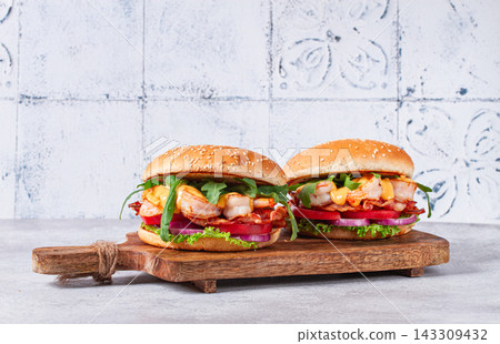 Shrimp burgers with fresh ingredients are served on a wooden board in a bright kitchen, Shrimp burgers with fresh ingredients are served on a wooden board in a bright kitchen, 143309432