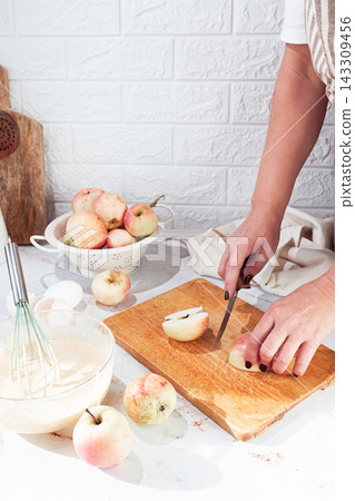 Cutting apples in a kitchen with a white brick wall and preparing for a recipe at home Cutting apples in a kitchen with a white brick wall and preparing for a recipe at home 143309456