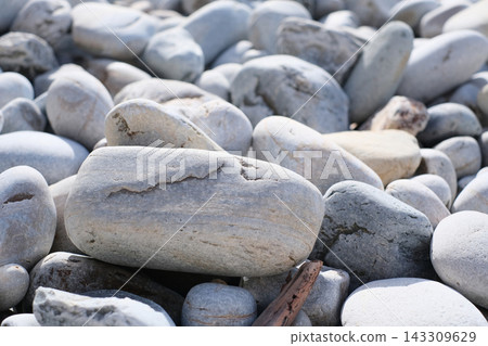 Close-up view of smooth, light grey river stones and pebbles lying on a natural beach. Close-up view of smooth, light grey river stones and pebbles lying on a natural beach. 143309629