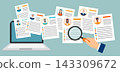 Employer hand holding magnifying glass and reviewing candidates  resumes on a laptop 143309672