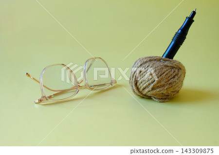 Glasses and Jute rope ball with pen on background. Glasses and Jute rope ball with pen on background. 143309875