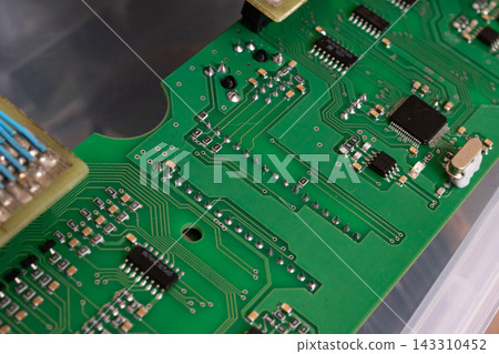 Green Circuit Board Close-Up with Microchips and Soldered Components Green Circuit Board Close-Up with Microchips and Soldered Components 143310452