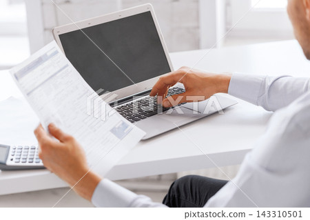 Business Finance Professional Working on Laptop with Documents Business Finance Professional Working on Laptop with Documents 143310501
