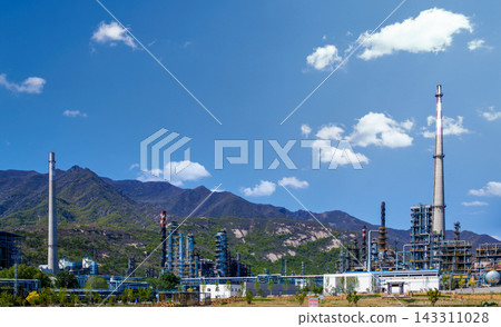 Industrial Plant with Smokestacks Against Mountainous Landscape Under Blue Sky Industrial Plant with Smokestacks Against Mountainous Landscape Under Blue Sky 143311028