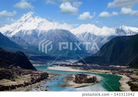 Majestic Snow Capped Mountains Overlooking a Turquoise River Valley in Tibet Majestic Snow Capped Mountains Overlooking a Turquoise River Valley in Tibet 143311042