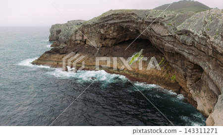 Sea cave in cliff along coastal rock formation Sea cave in cliff along coastal rock formation 143311271
